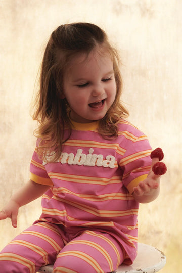 T-shirt dziecięcy różowy w kolorowe paski z napisem "Bambina" - She Is Sunday